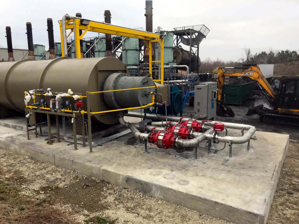 Green Horizontal Enclosed Flare with Red Valves and Yellow Piping installed on Cement Pad. Horizontal Enclose Flares Can Abate >99% DRE of VOC and HAP at Midstream Facilities