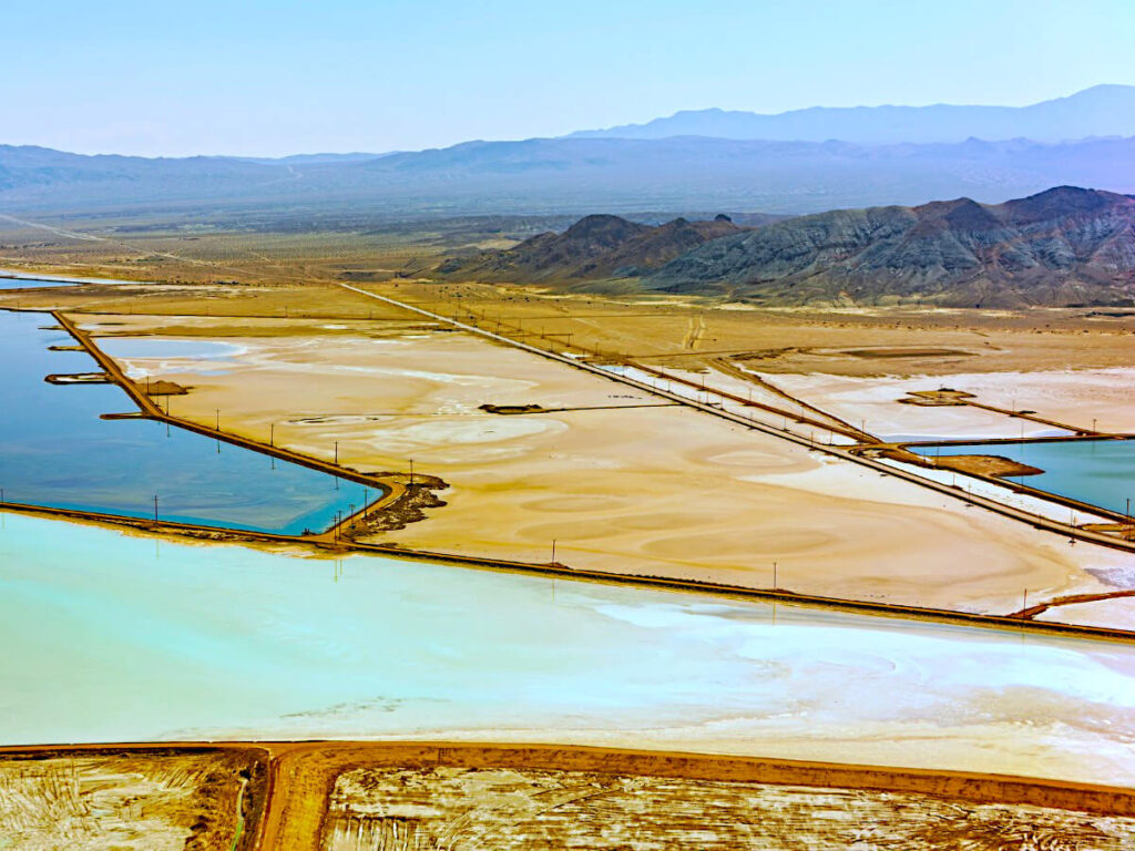 Plots of Blue to Orange Lithium Salt Ponds In Various Stages of Evaporation Outlined by Orange Dirt Roads. Lithium Salt is Collected Off of Ground Surface After Water has Evaporated