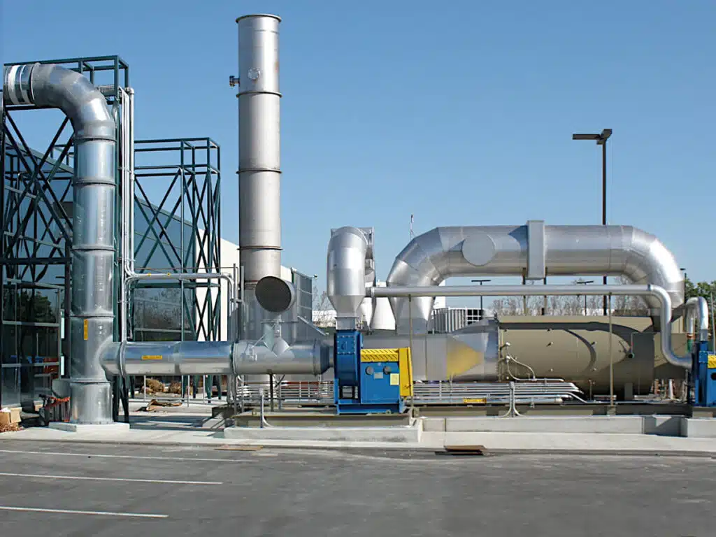 A Tan Catalytic Oxidizer with a Stainless Steel Stack and Ducts Destroys VOC at a Solar Panel Plant under a Clear Blue Sky